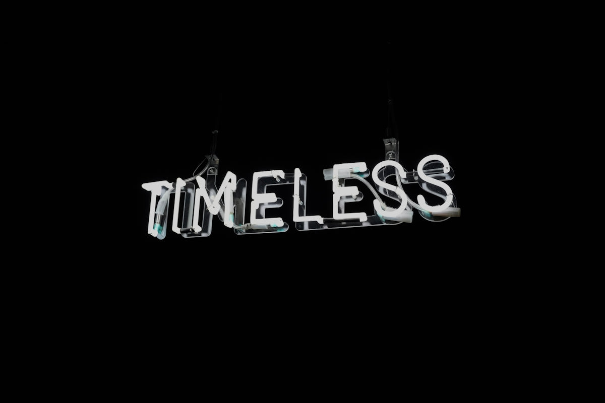 White neon word timeless on black background